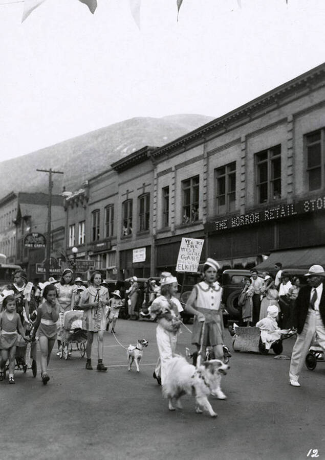 Children marching, walking their dogs, and pushing strollers during the Elks Roundup parade in Wallace, Idaho.