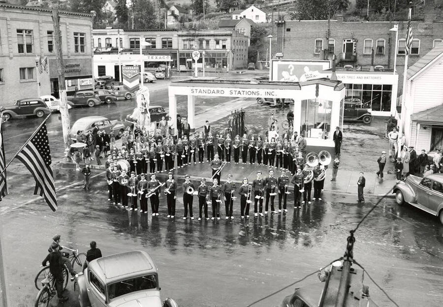 The Wallace High School Band standing in formation at the Standard Station in Wallace, Idaho. This was taken at the time of the fireman's convention.