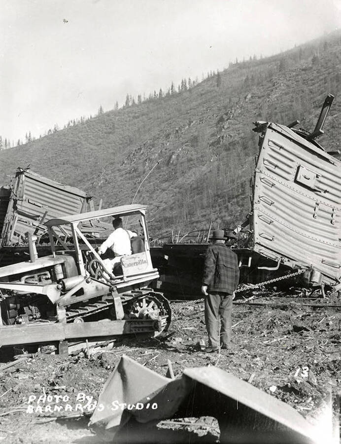 Damage to railroad cars, caused by the sunshine powder magazine explosion at the mouth of Big Creek. A man can be seen attempting to move the demolished railroad car.