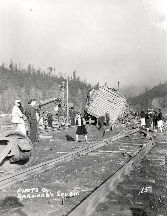 Damage to railroad cars, caused by the sunshine powder magazine explosion at the mouth of Big Creek. People are standing along the tracks looking at the damage.