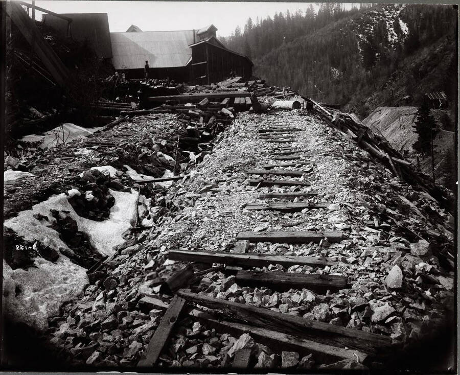 View of some scattered railroad ties on a gravel rail bed leading to some mine buildings. Caption on front: "Success Mine, Wallace, Taken for George R. Trask."