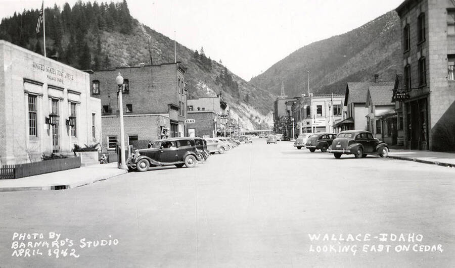 Looking east on Cedar Street in Wallace, Idaho.  Cars are parked out in front of stores, which line the street.