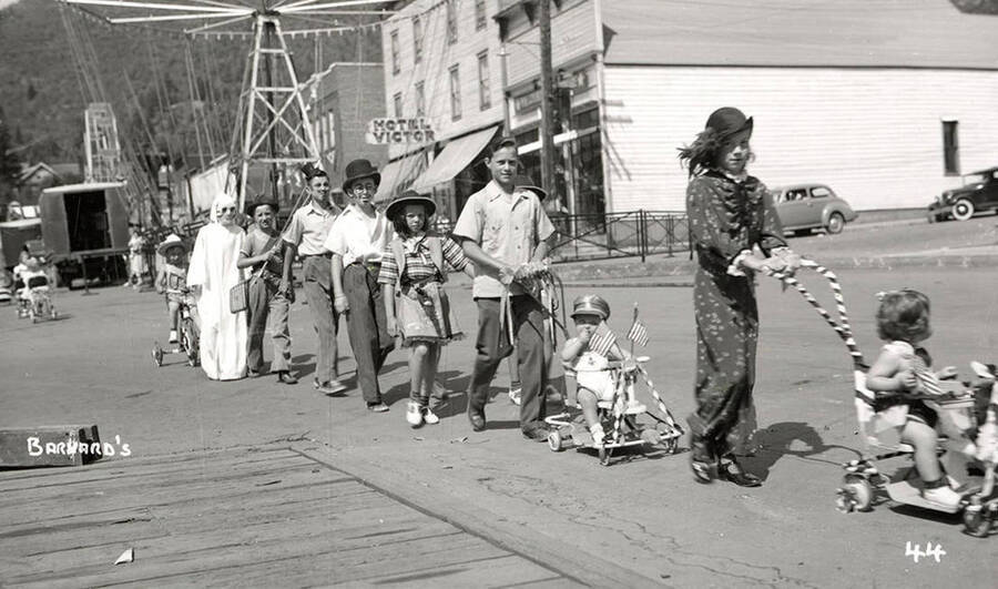 Children, who are in costume, walking in the Mullan 49'er parade in Mullan, Idaho. Some children are pushing smaller ones in strollers.