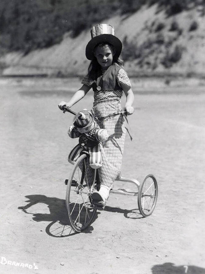 A girl, who is in costume, riding a bicycle during the Wallace pet parade in Wallace, Idaho.