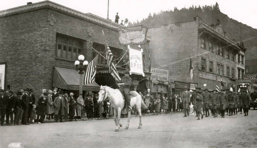 A man riding a horse while a group of people walk behind him during Elks parade in Wallace, Idaho.