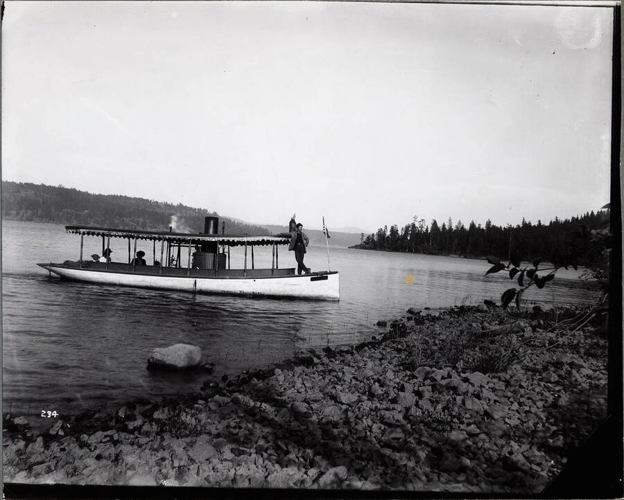 Photograph of the steam launch Juliette taking off from Lake Coeur d'Alene with five passengers.
