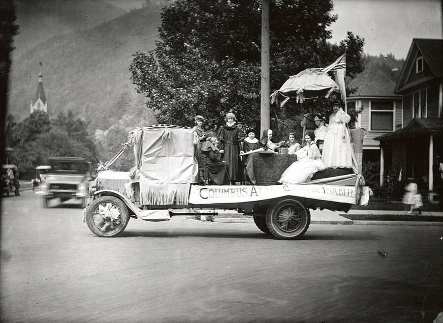 A group of people sitting around a table on the "Columbus at the Court of Isabell" float in the Fourth of July Parade in Wallace, Idaho.