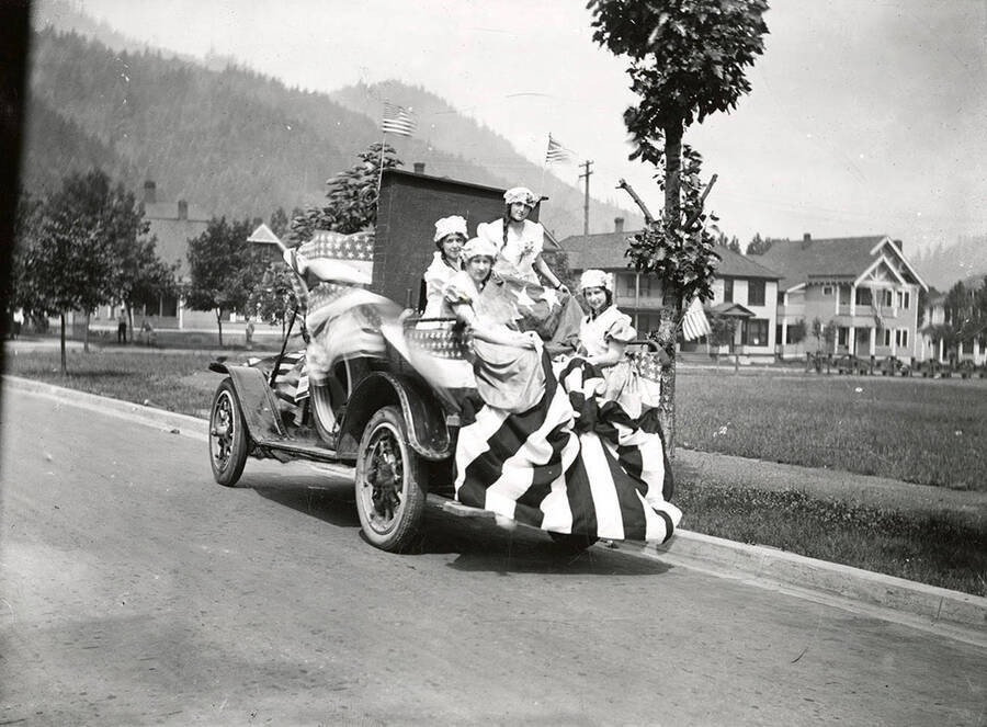 Four women sitting on a float being driven in the Fourth of July Parade in Wallace, Idaho.