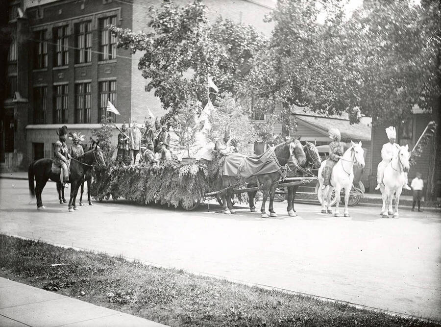 People riding horses next to a float being pulled by horses in the Fourth of July Parade in Wallace, Idaho.