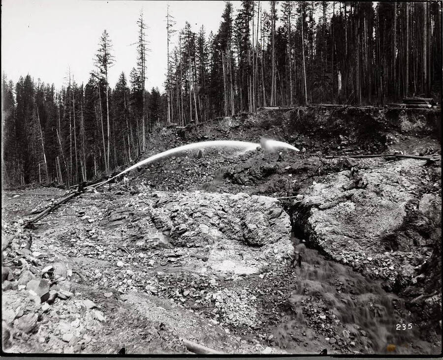 Image show a group of miners using an hydraulic placer mining method, common to many claims in the Coeur d'Alene mining district. Caption on front: "Spokane Hydraulic Placer Mining."