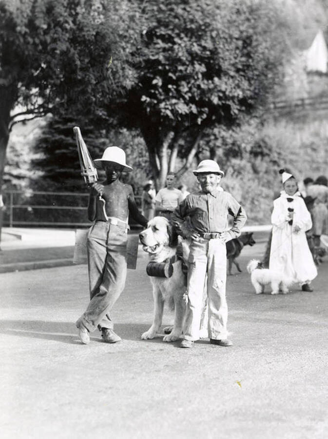 Two boys in costume standing with their dog during the Slippery Gulch parade in Wallace, Idaho.