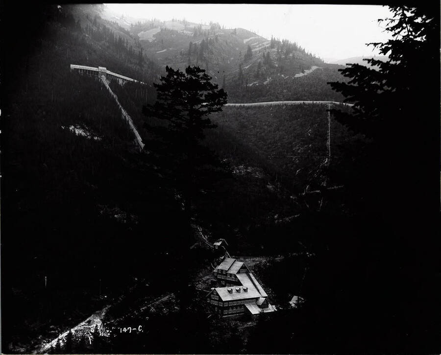 Image of the Hercules Mill in Burke, Idaho, taken from the opposite hillside, with  trees obscuring part of the photograph.