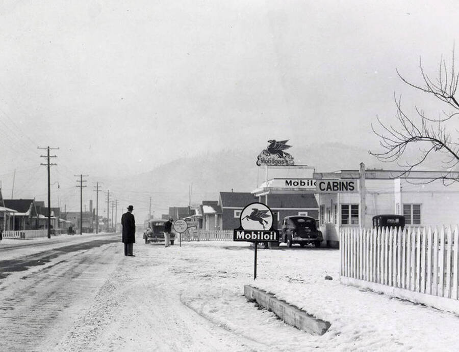 Exterior view of the Mobiloil gasoline station in Wallace, Idaho. A man can be seen standing on the street in front of the station. Taken for Keane & McCann, lawyers.
