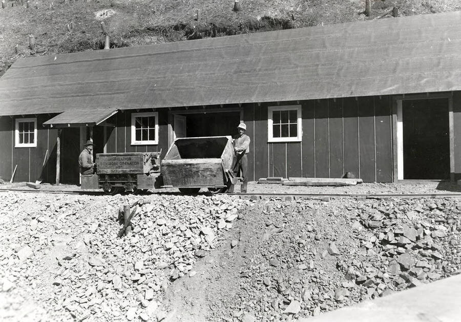 Two men standing with dumping ore carts at the Silverore-Inspiration Silver Mine in Osburn, Idaho.