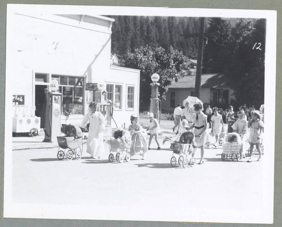 Children and an adult in costume pushing babies in carriages during the Children's Parade.