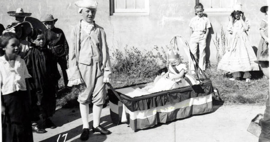 Children in costume during the 49'er Parade in Mullan, Idaho. A small child is being pulled along in a decorated wagon.