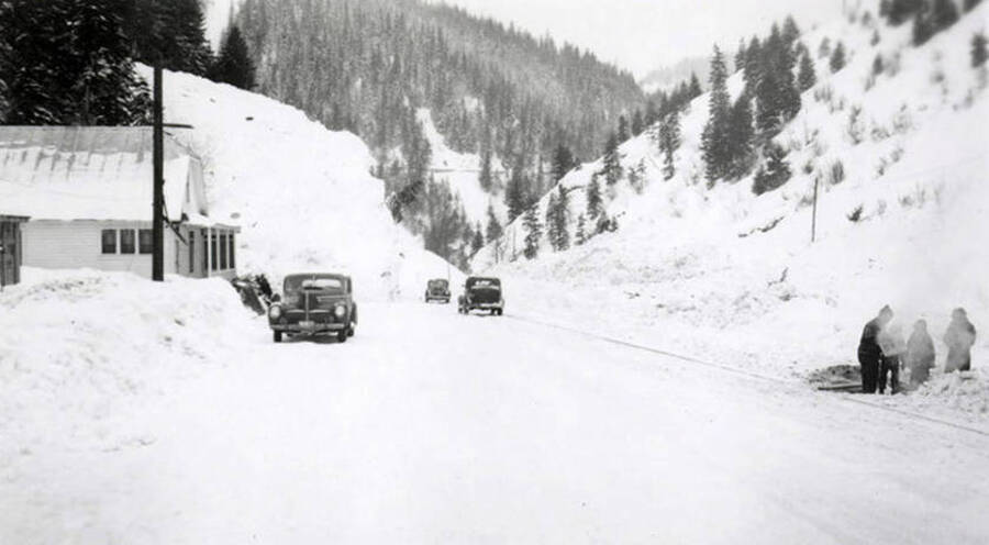 People and cars along a snow covered road in historical Yellow Dog, Idaho, after a snow slide.