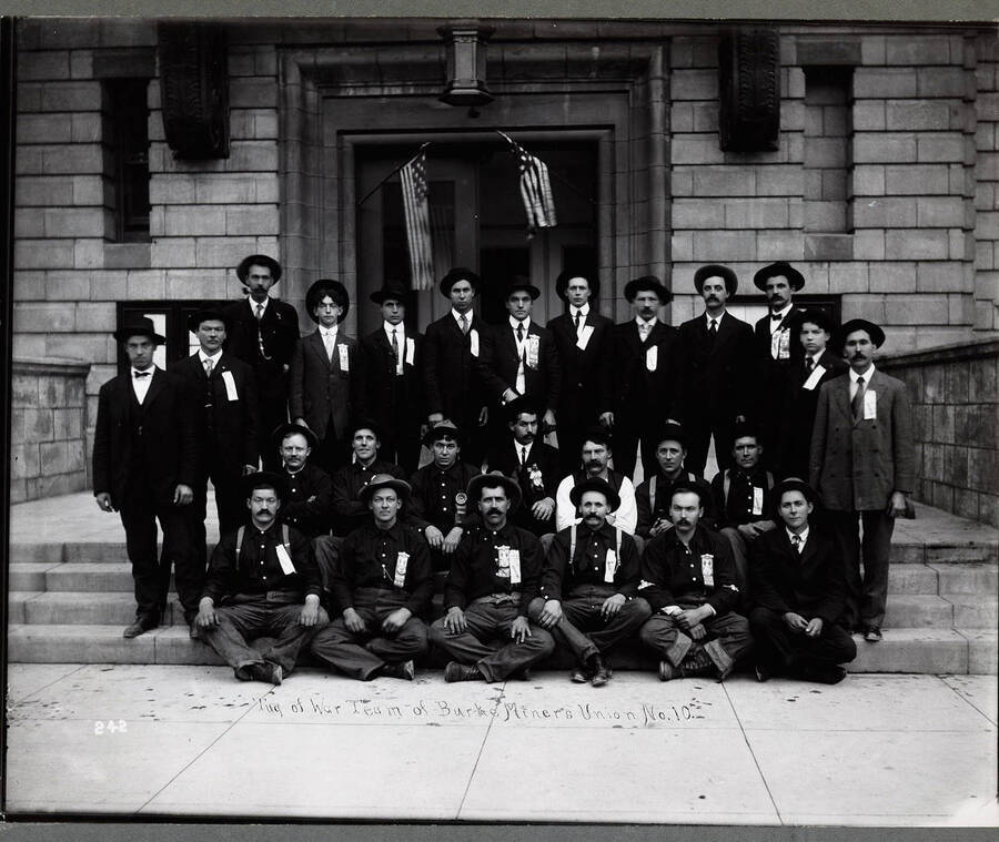 Group photo of the Burke Miners Union No. 10 tug-of-war team, taken outside of an unidentified building. Caption on front: "Tug of War Team of Burke Miners Union No. 10."