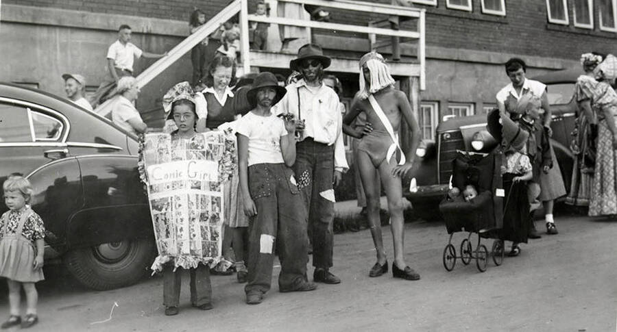 Children in costume during the 49'er Parade in Mullan, Idaho. To the left, a young girl is wearing a costume made out of various comic strips, with "Comic Girl" written across the front.