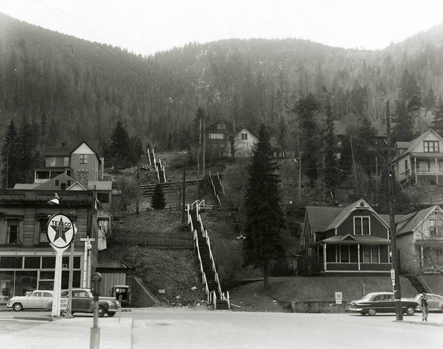 View of the steps on Fifth Street in Wallace, Idaho. A Texaco gas station, houses, and buildings can be seen around the steps.