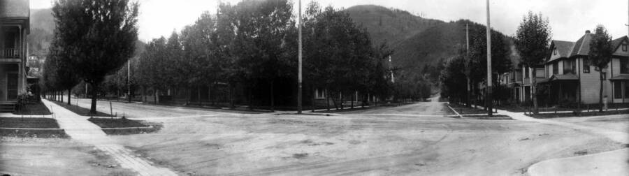 View of a street corner with houses and trees. Panoramic photograph of Wallace, Idaho.