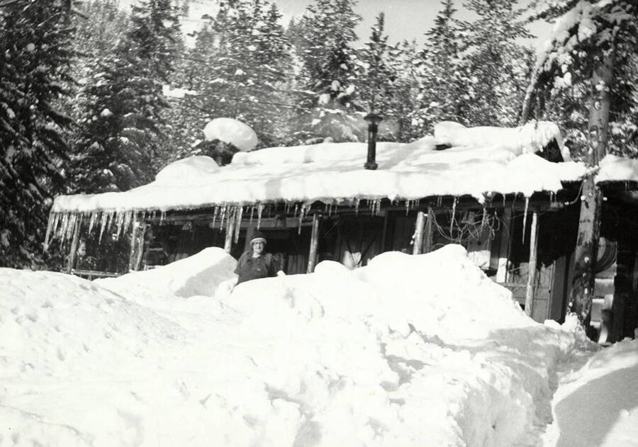 A man standing in front of a snow covered Tobs cabin near Wallace, Idaho.