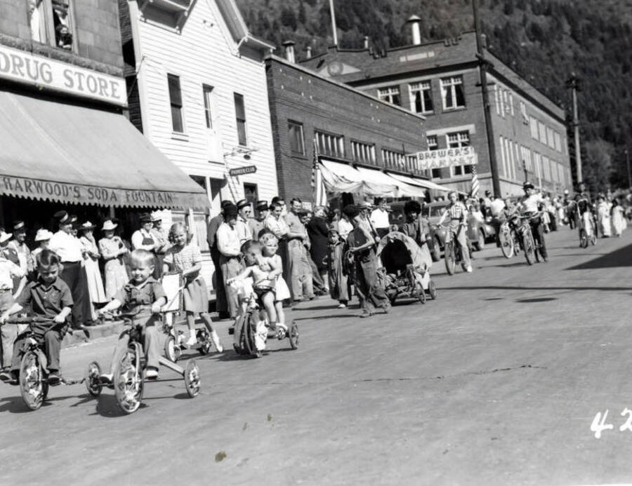 Children riding bikes and pulling wagons during the 49'er Parade in Mullan, Idaho.