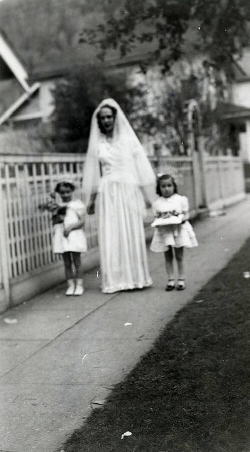 A woman with two children on the sidewalk outside of Our Lady of Lourdes Academy during the Blessed Virgin Procession in Wallace, Idaho.