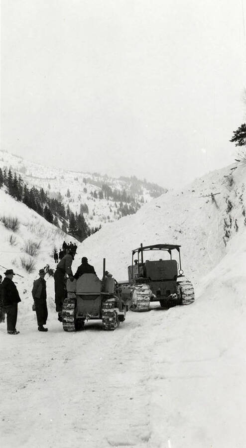 People using tractors to remove snow in historical Yellow Dog, Idaho, after a snow slide.