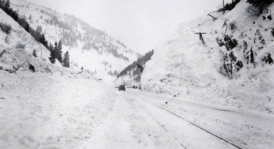 People and cars along a snow covered road in historical Yellow Dog, Idaho, after a snow slide.