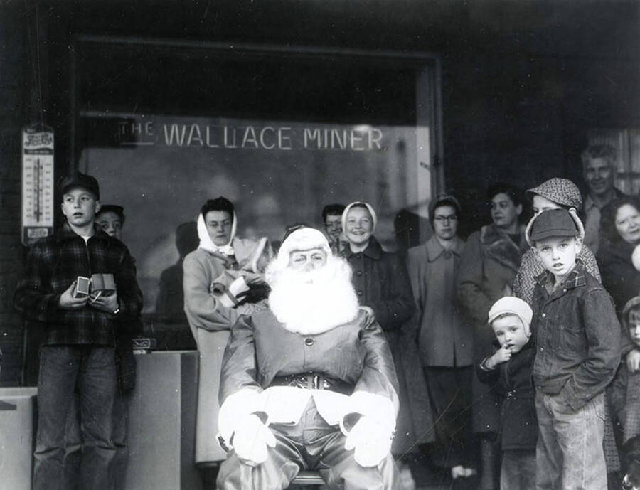 Santa Claus sitting with children in front of the Wallace Miner window.