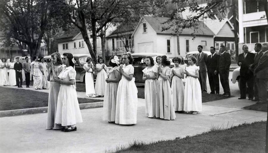 Children lined up on the sidewalk outside of Our Lady of Lourdes Academy during the Blessed Virgin Procession in Wallace, Idaho.