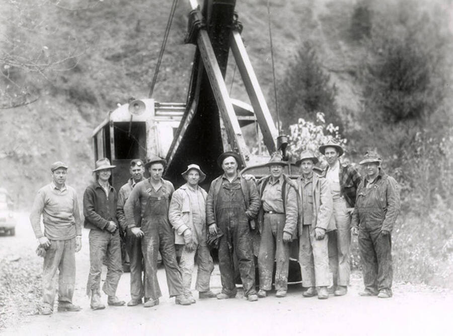 A group photograph of the Colonial Construction Company crew gathered in front of a large tractor.