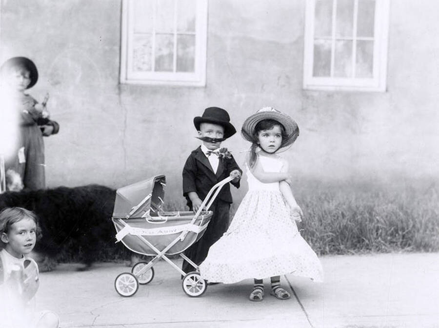 Two small children posing in costume next to a baby carriage during the 49'er Parade in Mullan, Idaho.