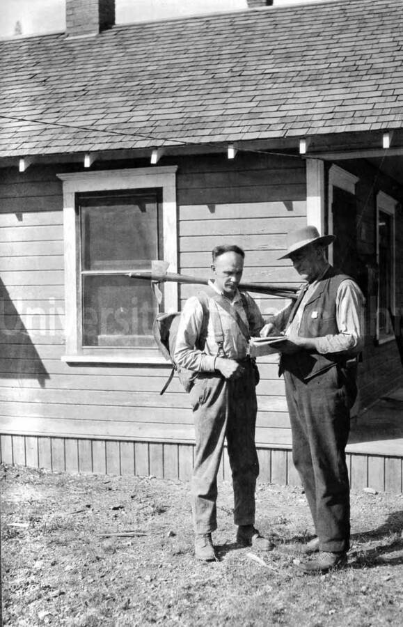 Images shows two men standing in the yard of a home. 1910 Forest fire