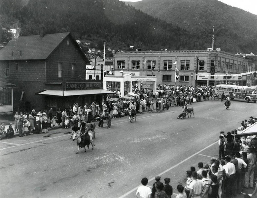 Donkeys being ridden in the Jubilee parade in Wallace, Idaho. The negative was developed backwards, hence Brooks Hotel appears on the wrong side of the street.