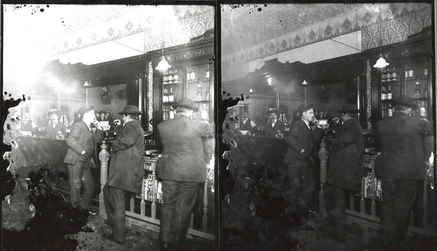 Portrait of Dooling's Saloon in Mullan, Idaho. The owner, Larry Dooling, can be seen in the background. This is two prints of the same negative, with one slightly under-developed. The negative suffered severe degradation before being printed.