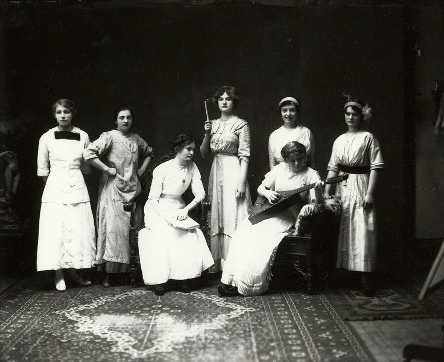 Group photos of the members of the Wallace High School play Trouble at Scatterlees. Seven girls are posed in costume. Four of the actresses were Catherine McDonald, Gladys Evans, Lucille Mahoney and McClellan Beulah.