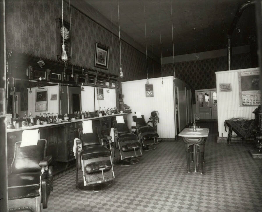 Interior view of the of O.K. Barber Shop in Wallace, Idaho. Four barber chairs, a sink, and various equipment can be seen.