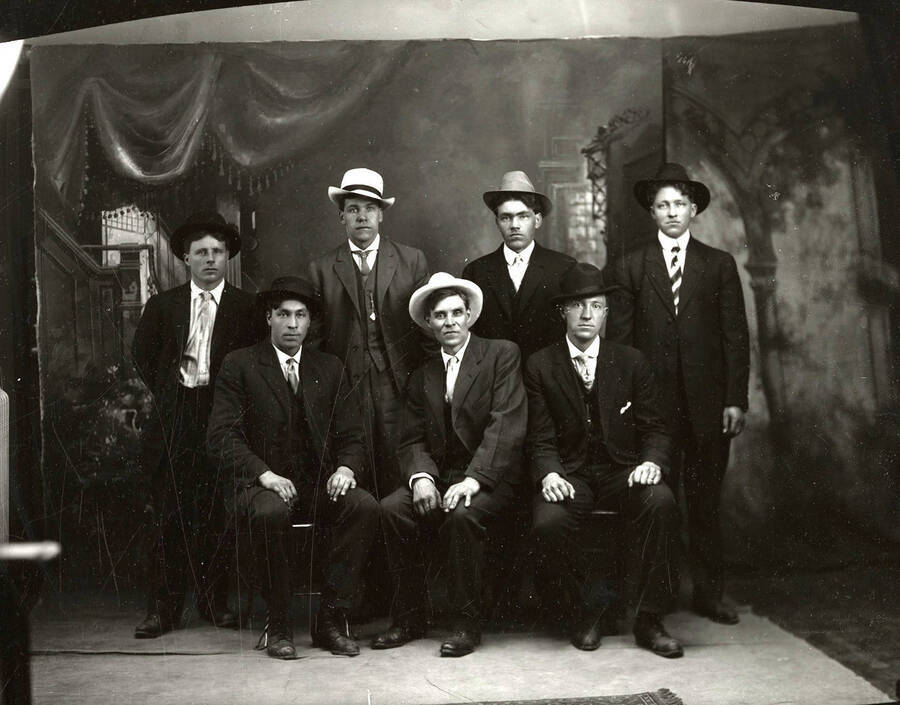 Group photo of seven men, all wearing hats. Three men can be seen seated with four men standing behind them.