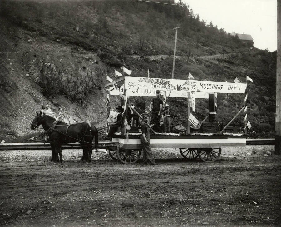 A decorated wagon with a sign saying "James Slete, the youngest moulder in the world" during the 4th of July parade in Wallace, Idaho.