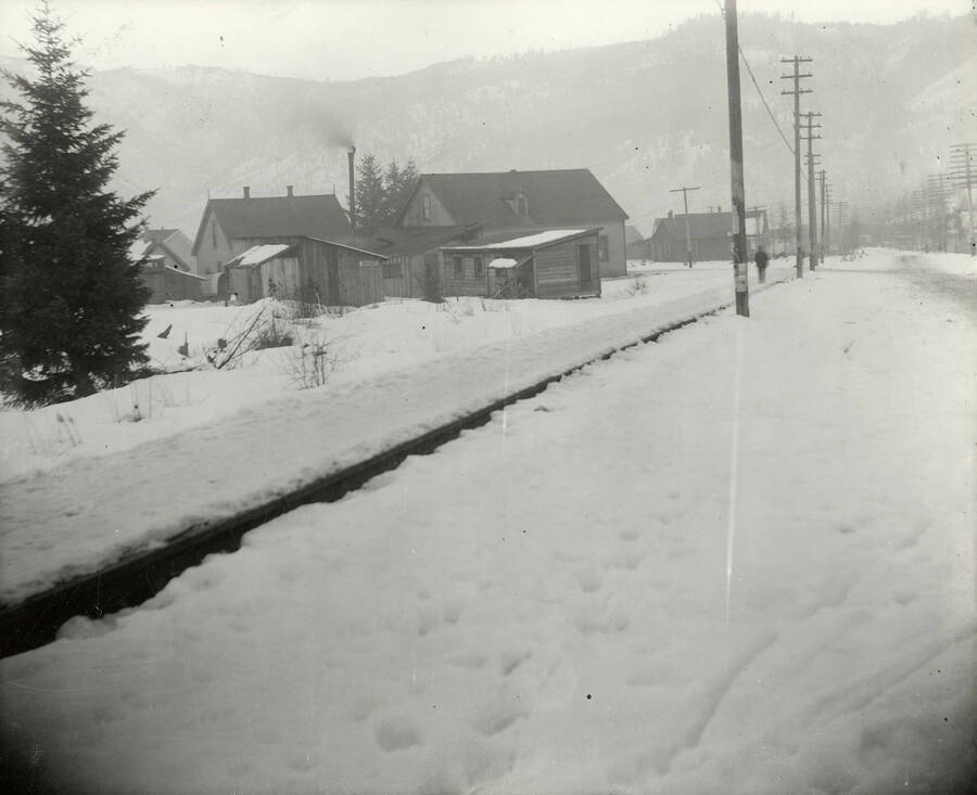 View of the residential area in Kellogg, Idaho during the winter. A person can be seen walking on the sidewalk. This photo was taken for J.A. Wayne.