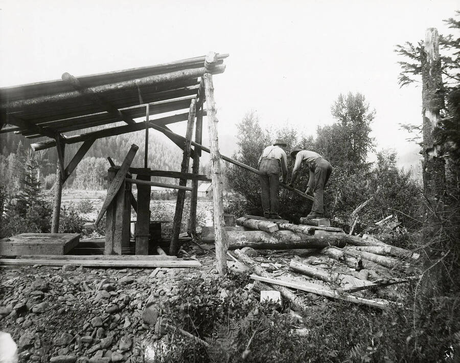 Men mining at Eagle creek, which is located on the north side of the Coeur d'Alene Mining District. The men can be seen operating a pump.