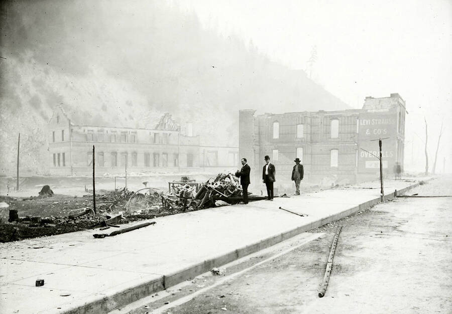 The remains of a brick building at 721 Bank Street in Wallace, Idaho after a fire. The OR&N depot can be seen in the background.