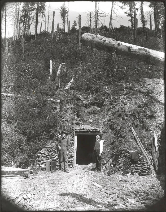 Two men standing outside of the entrance to an unidentified mine.