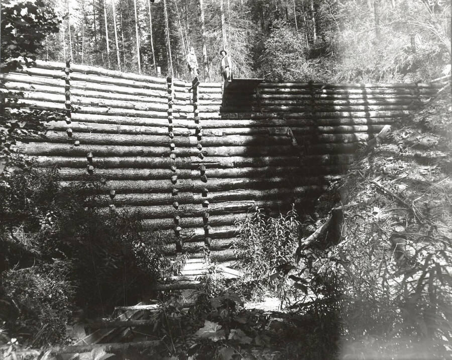 North side, Coeur d'Alene Mining District (Murray area). An unidenified man stands on top of the dam face.