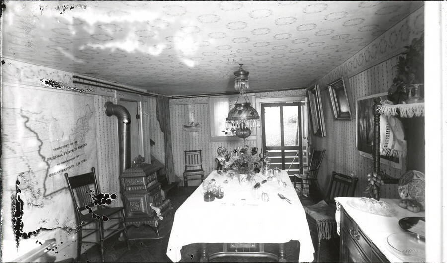 A photograph of the dining room in Barry N. Hillard's home. Some slight bubbling and degradation on the glass negative caused some distortions on the left side of the image.