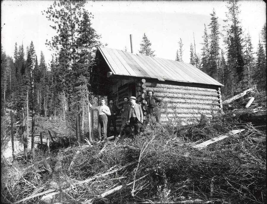 Five men standing in front of a cabin at an unidentified mining camp site.