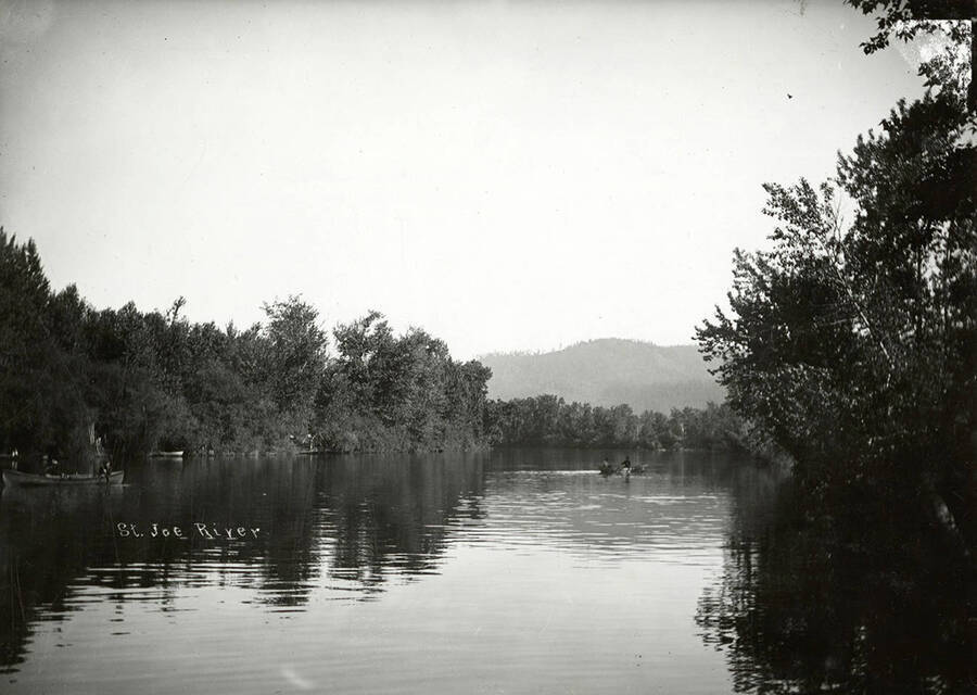 View of the St. Joe River. People in small boats can be seen out on the water.