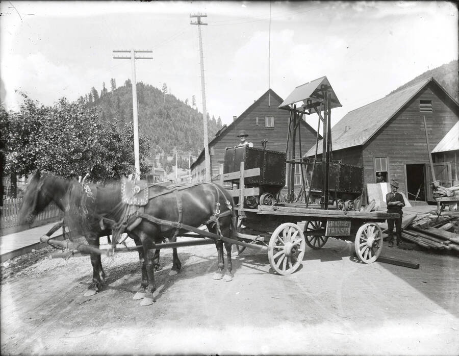 Ore cars being hauled out of Coeur d'Alene Hardware and Foundry by George K. Garrett Transfer on a horse-drawn wagon.
